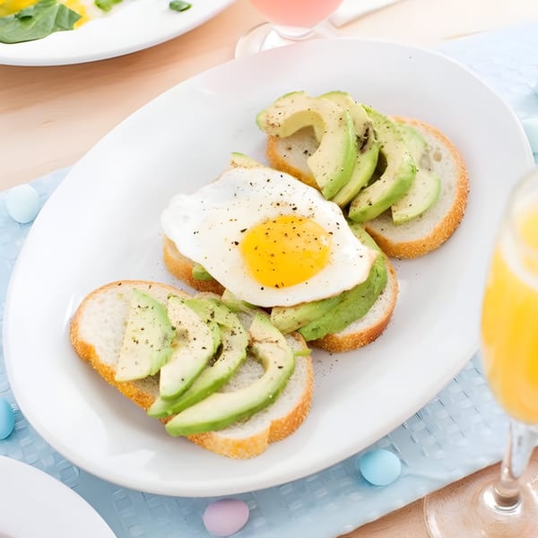 Three slices of avocado toast, one topped with a fried egg, on a white plate.