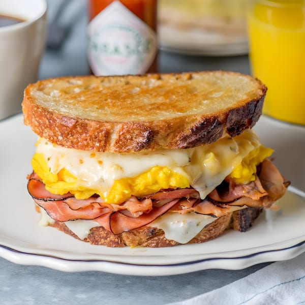 A Chops & Eggs breakfast sandwich with scrambled eggs, melted cheese, and ham on toasted bread.